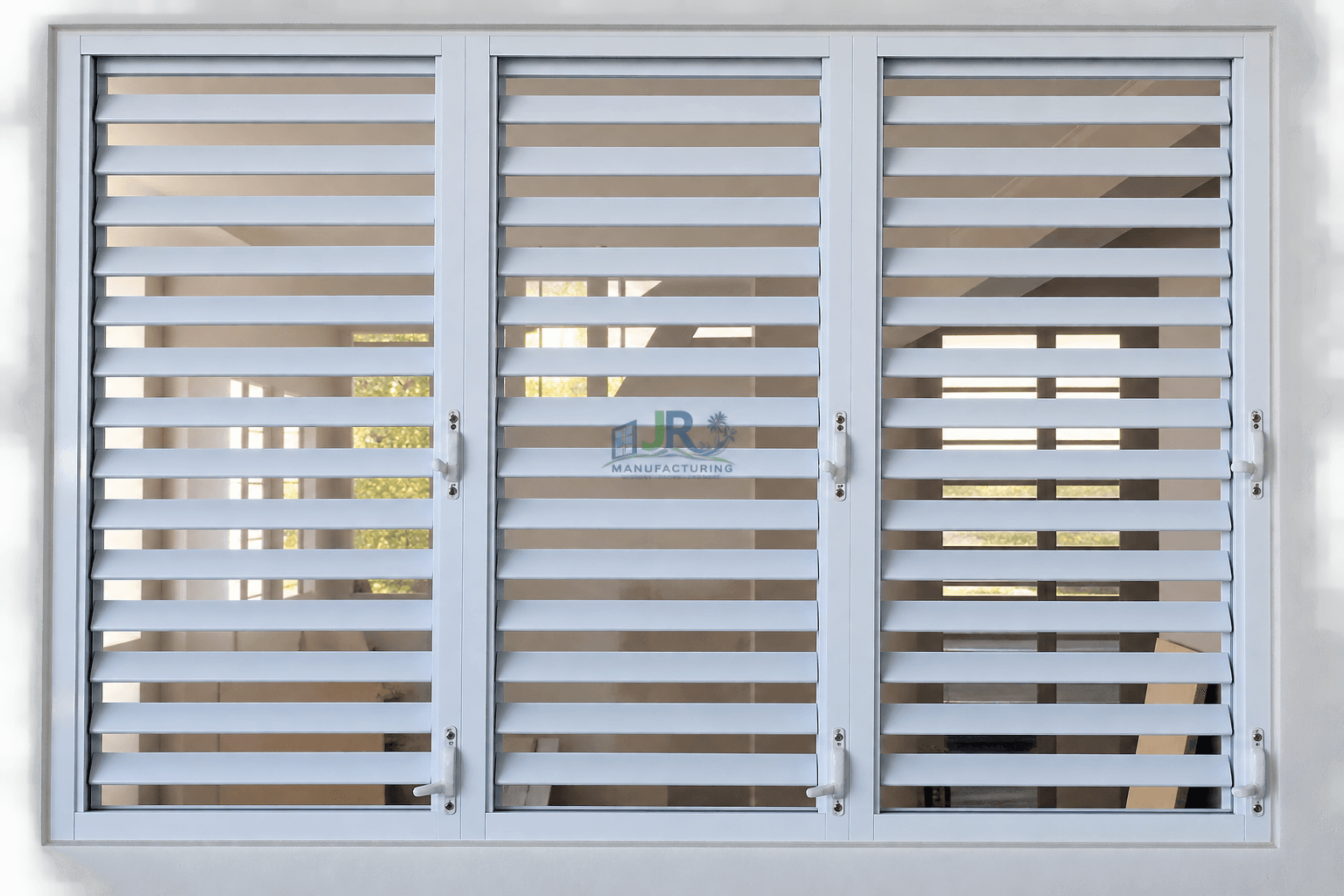 White three-panel jalousie window with horizontal slats and white handles, set in a wall.