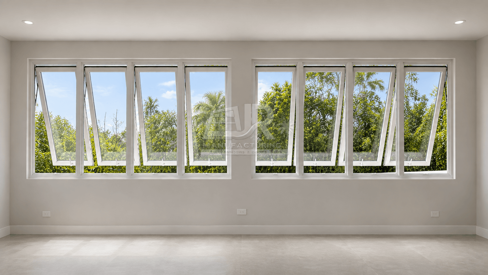 White-framed awning windows tilted open, revealing lush green trees in a bright, empty room.
