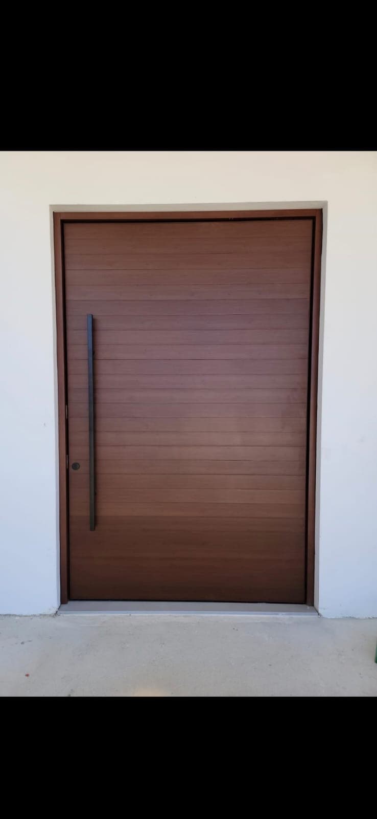 Modern dark brown wooden door with horizontal planks and a long vertical black handle.