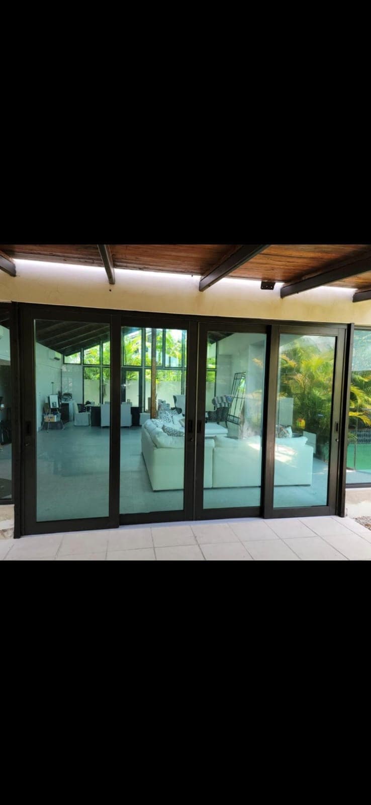Modern black-framed sliding glass doors revealing a bright interior with a white sectional sofa.