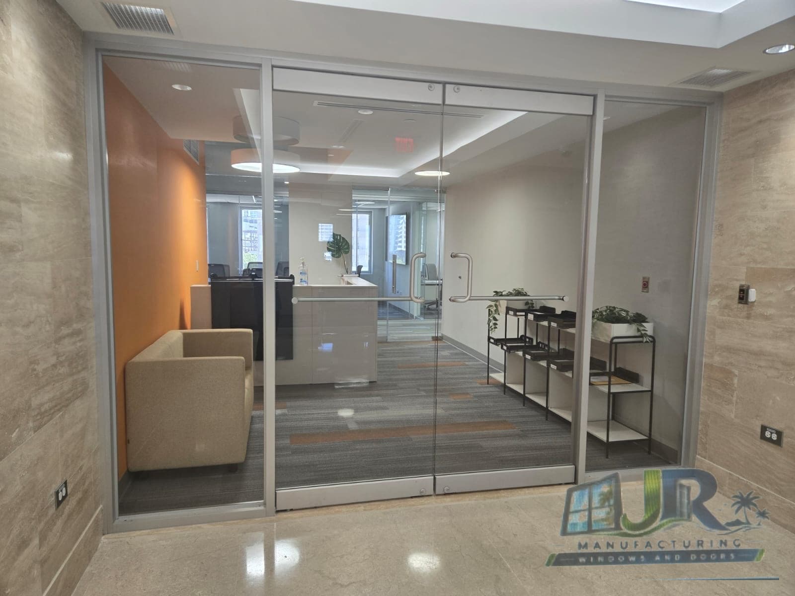 Modern double glass doors opening into a professional office lobby with an orange accent wall.
