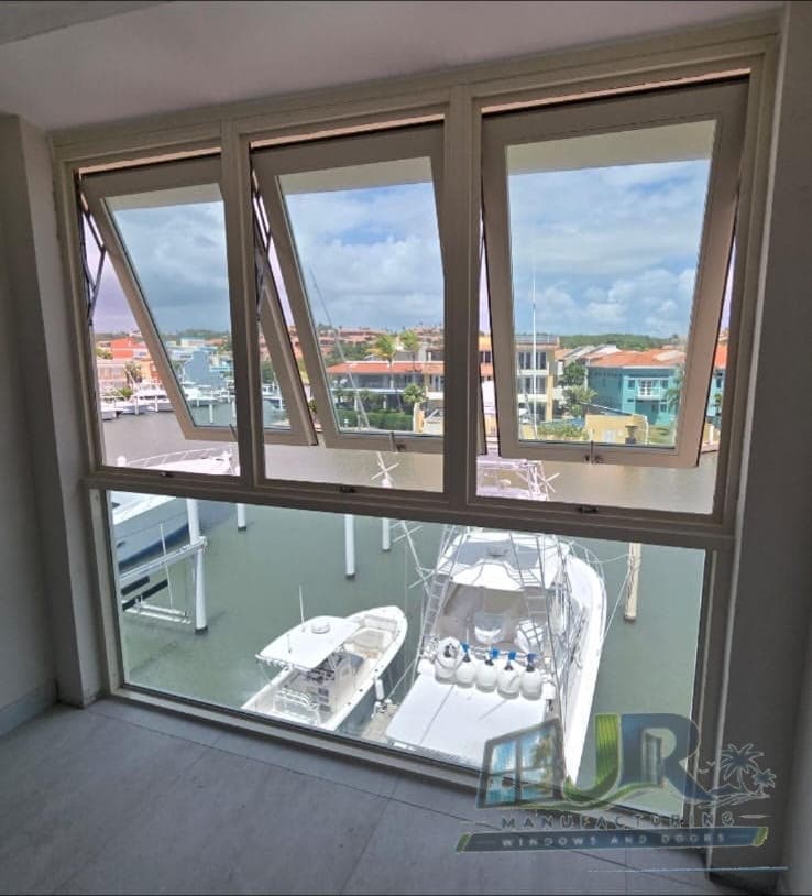 White windows open to a view of yachts in a marina and waterfront homes.